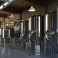 Row of stainless steel brewing tanks and fermenters inside the brewhouse