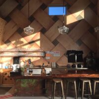 Tasting room bar with wood stools and a cedar wall in a woven pattern
