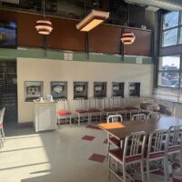 Restaurant dining room with a new cream wall holding a row of self-serve frozen yogurt dispensers