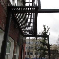 Underside of a retrofitted fire escape platform and stair bolted to the brick wall