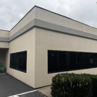 Corner of the office building with its service entry and parking area before new siding