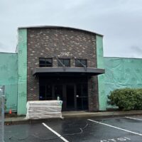 Brick entry of the office building with the walls wrapped in weather barrier during recladding